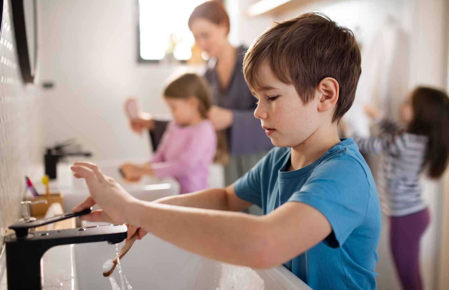 Bambino in primo piano che lava lo spazzolino in autonomia per imparare a rispettare l'ambiente